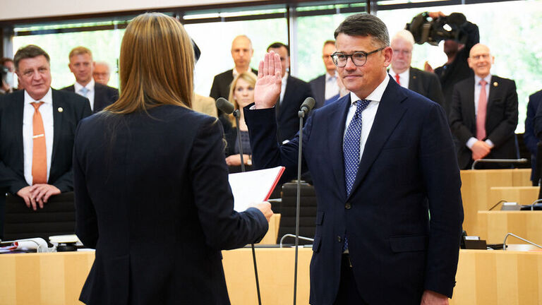 Ministerpräsident Boris Rhein steht im Hessischen Landtag und wird von der Landtagspräsidentin vereidigt.