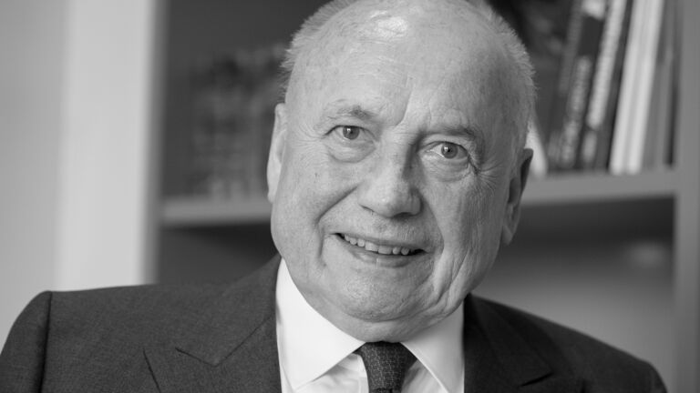 Ein schwarz weißes Bild mit einem lächelnden Herren im Anzug