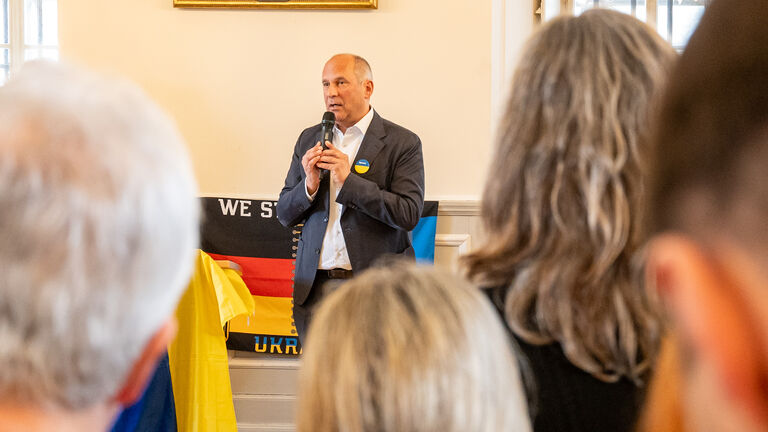 Mann mit Mikrofon spricht zu Publikum