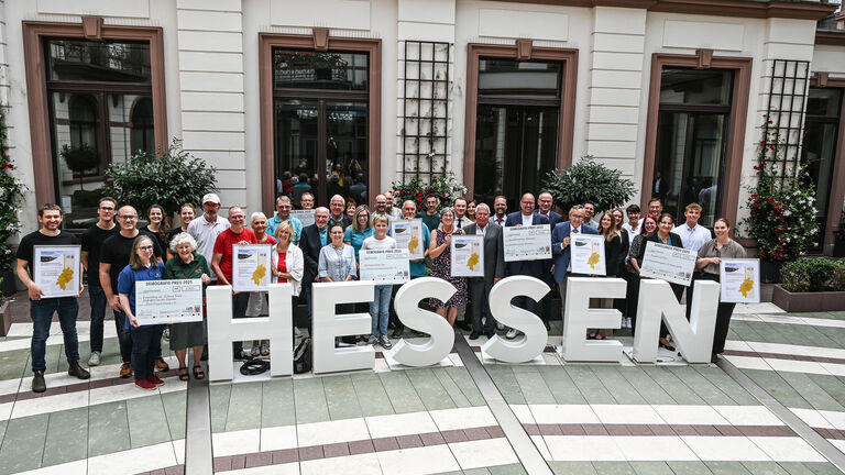 Eine große Gruppe Menschen steht hinter den Buchstaben Hessen