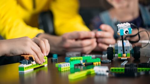 Bots aus Bausteinen bauen Junge Hände setzen einen Roboter aus Lego zusammen