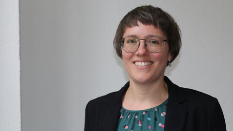 Franziska Richter Franziska Richter lächelt frontal in die Kamera. Sie trägt ein schwarzes Jacket und eine dunkelgrüne Bluse mit bunten Punkten.