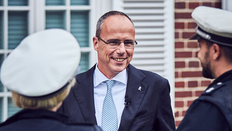 Innenminister Peter Beuth Minister Beuth im Gespräch mit einer Polizisten und einem Polizisten, die von hinten zu sehen sind.