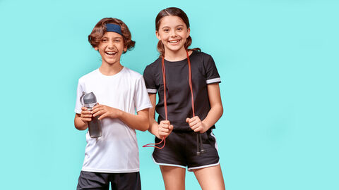 Sportlich und gut ausgestattet Zwei junge Teenager in Sportkleidung stehen vor einem türkisen Hintergrudn und lachen in die Kamera