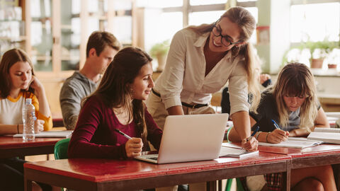 Lehrerin im Unterricht im Gespräch mit einer Schülerin Lehrerin im Unterricht im Gespräch mit einer Schülerin