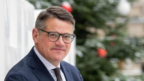 Ministerpräsident Boris Rhein steht vor einem Weihnachtsbaum und schaut in die Kamera