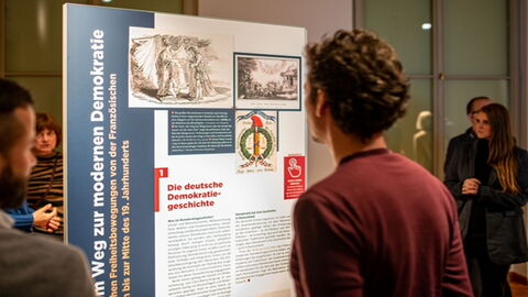 Ausstellungseröffnung Mann schaut sich Plakat an