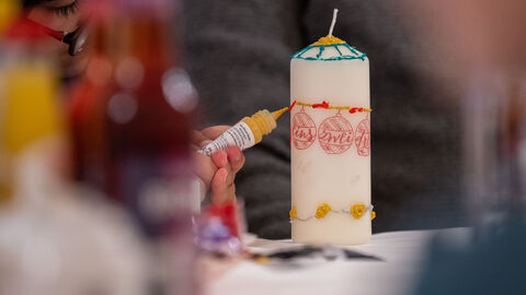 Künstlerin am Werk Eien große Kerze wird verziert