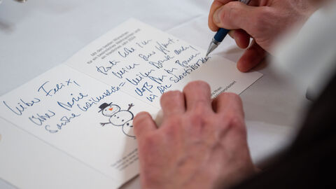 Der Ministerpräsident schreibt einen Weihnachtsgruß an Felix Nahaufnahme: eine Karte mit Schneemann wird beschriftet