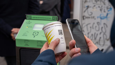 Rückgabe eines Bechers am Automaten Person scannt mit Smartphone den QR-Code eines Bechers