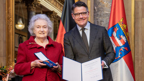 Zwei Personen stehen nebeneinander und halten die Auszeichnung hoch.