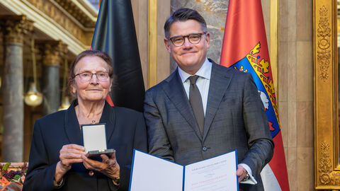 Zwei Personen stehen nebeneinander und halten die Auszeichnung hoch.