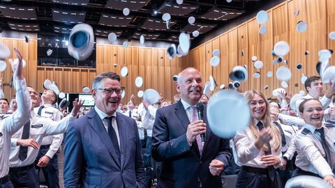 Vereidigung Hessentag 2025 Ministerpräsident Boris Rhein und Innenminister Roman Poseck stehen inmitten von Menschen, die ihre Mützen in die Luft werfen.