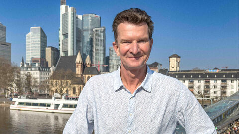 Ein Mann steht auf einer Brücke. Im Hintergrund sind Hochhäuser.