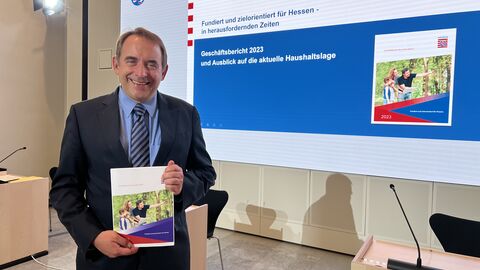 Hessens Finanzminister Professor Dr. R. Alexander Lorz stellt den Geschäftsbericht 2023 vor. Zu sehen ist Hessens Finanzminister Professor Dr. R. Alexander Lorz im Presseraum des Hessischen Landtags, er hält den Geschäftsbericht 2023 in seinen Händen.