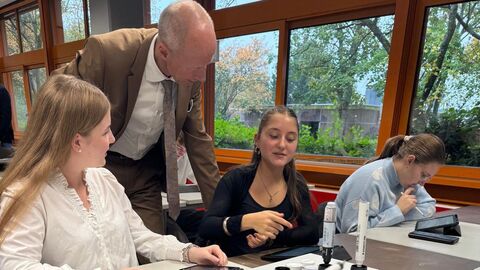 Bildungsminister Armin Scharz beim Gespräch mit Schülerinnen. Bildungsminister spricht mit Schülerinnen in einem Klassenzimmer.