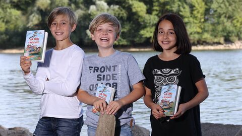 Drei Kinder mit dem Comicroman „Iva, Samo und der geheime Hexensee“ zum Welttag des Buches 2022. Drei Kinder mit dem Comicroman „Iva, Samo und der geheime Hexensee“ zum Welttag des Buches 2022.