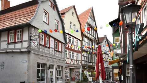 Den zweiten Platz des Hessischen Denkmalschutzpreises 2022 in der Kategorie "Privates Bauen" bekam Rudolf Knierim für sein Projekt Haus Helbig in Alsfeld - hier in der Mitte der Häuserzeile links zu sehen. Eine Fachwerkhäuser-Zeile in Alsfeld; das Haus in der Mitte, beige-hellbraun gehalten mit historischen Fotos im Schaufenster im Erdgeschoss, ist das Preisträgerobjekt