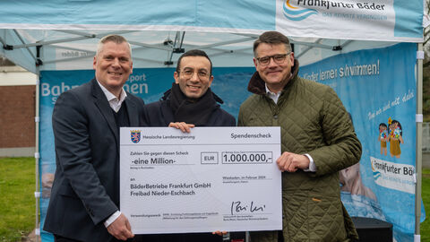 Förderung Traglufthalle im Freibad Nieder-Eschbach Ministerpräsident Boris Rhein hält gemeinsam mit Dr. Boris Zielinski sowie dem Oberbürgermeister der Stadt Frankfurt und Aufsichtsratsvorsitzenden der Frankfurter BäderBetriebe GmbH Mike Josef einen Scheck in die Kamera